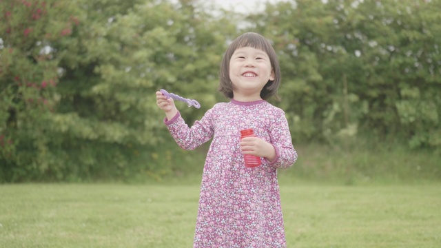 蹒跚学步的小女孩在自家花园里玩肥皂泡视频素材