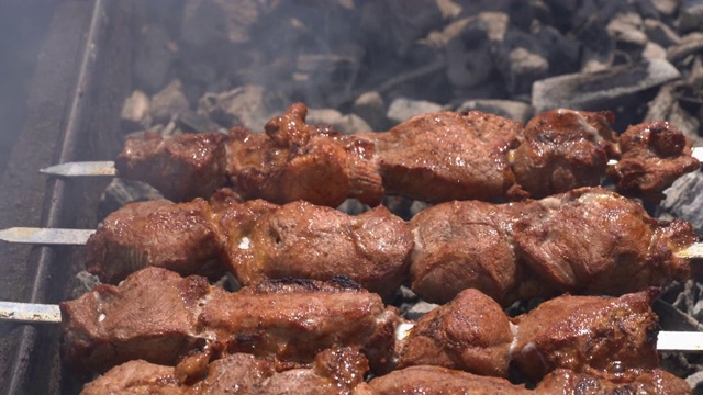 多汁的猪肉串在木炭烤架上的金属串上烹饪视频素材