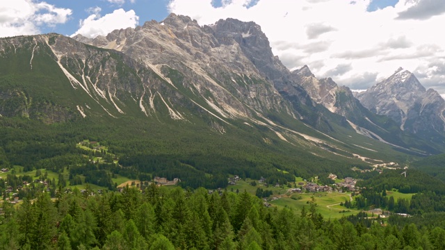 意大利Cortina d’ampezzo镇的山谷。白云石(意大利阿尔卑斯山)和松树林在山谷中对抗戏剧性的多云天空的全景。平移,4 k视频素材