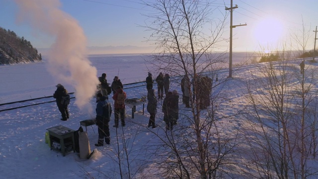 夕阳西下，人们站在贝加尔湖积雪覆盖的铁轨上视频素材