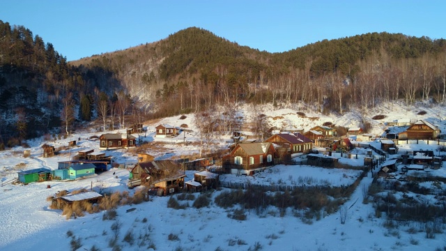 航拍:无人机在俄罗斯贝加尔湖上空的雪山景观中接近居民区视频素材