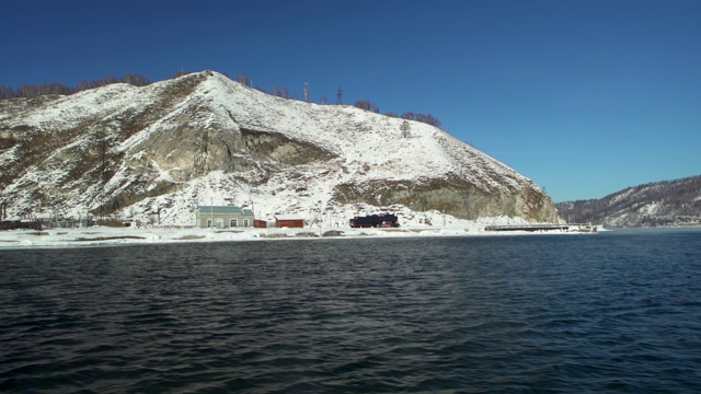 冬天，雪山和贝加尔湖边的房子映衬着湛蓝的天空视频素材