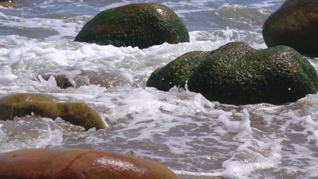 慢动作的海浪撞击覆盖着苔藓的海洋岩石视频素材