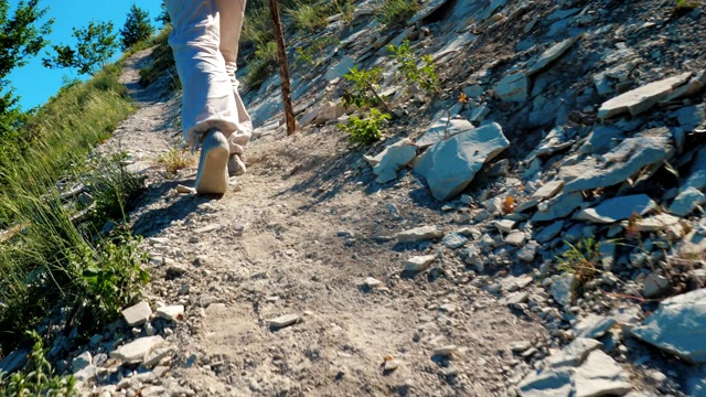 这个女旅行者正走在山里一条尘土飞扬的小路上。视频素材