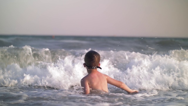 孩子在海里洗澡，海浪打到了他视频素材