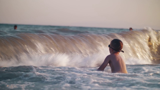 海浪打在孩子身上，溅了他一身水花视频素材