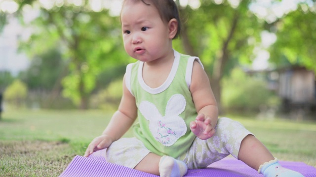 一个亚洲女婴在公园的绿草地上爬行。幸福的家庭的概念视频素材