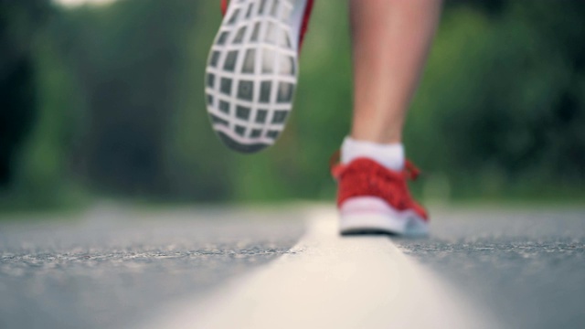 近距离的道路表面与跑步女性的脚在运动鞋视频素材