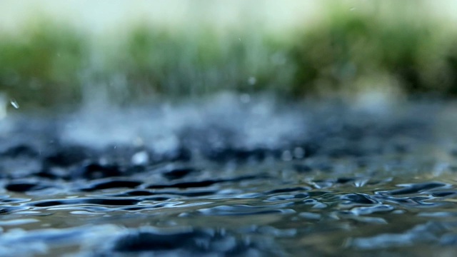 近距离的雨水滴落到水面在雨季视频素材