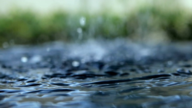 近距离的雨水滴落到水面在雨季视频素材