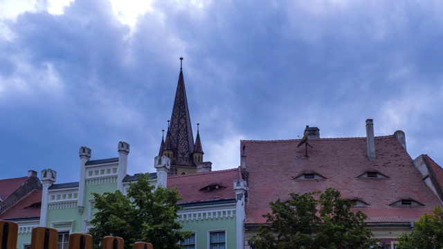 时间:罗马尼亚西比乌(Hermannstadt)小广场上戏剧性的暴风雨云和日落天空，传统房屋的窗户酷似人眼。放大4 k。视频下载