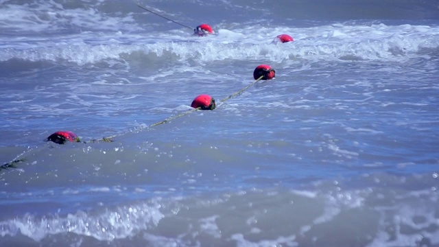 用绿色海藻围起来的红色旧浮标漂浮在海上的波浪上视频素材