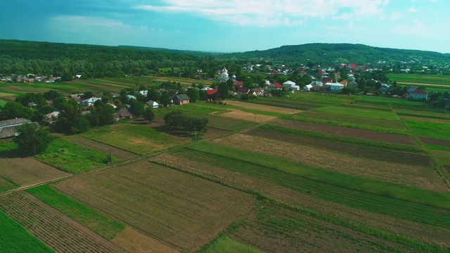 鸟瞰图，半全景平移移动。小居住区靠近耕地。4 k。视频素材