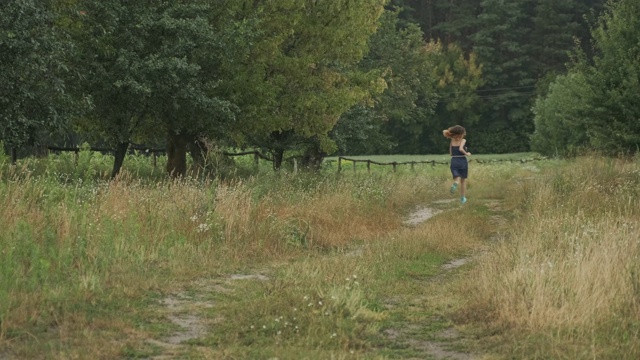 穿着衣服在乡间路上奔跑的少女，自然背景的乡村风格，背后的风景视频素材