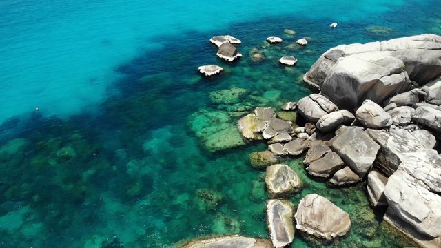 石头附近有平静的海水。在泰国阳光明媚的日子里，宁静的蓝色海水和灰色的巨石是潜水的完美场所。自然背景纹理。视频素材