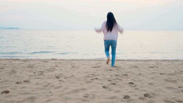 4 k。快乐的女人在热带的海滩上享受暑假，赤脚跑到海边，带着快乐的感觉跳跃视频素材