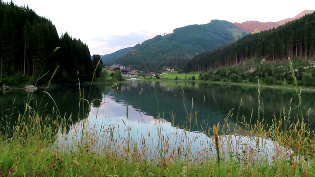 晚上在Tirol(奥地利)的Gerlos湖。水映山映林。村子里的背景。视频素材