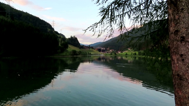 晚上在Tirol(奥地利)的Gerlos湖。水映山映林。村子里的背景。视频素材