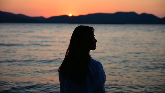 女人站在海滩上的海上日落背景在傍晚黄金时间。暑假去泰国海滩旅游视频素材