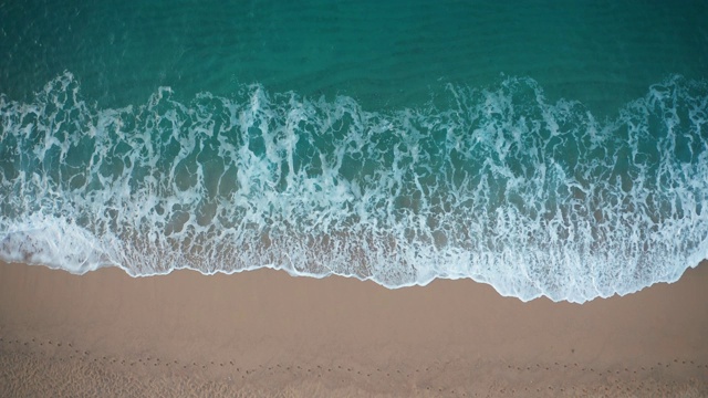 俯视图蓝色的海浪撞击沙滩视频素材