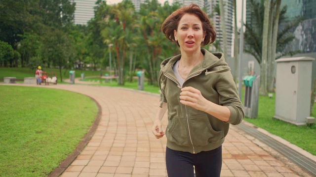 户外实时云台拍摄跟踪年轻迷人和健康的女人在绿色城市公园跑步在晨跑健康锻炼视频素材