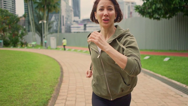 户外慢动作云台拍摄跟踪在慢动作年轻迷人和健康的女人在绿色城市公园晨跑慢跑健康锻炼视频素材