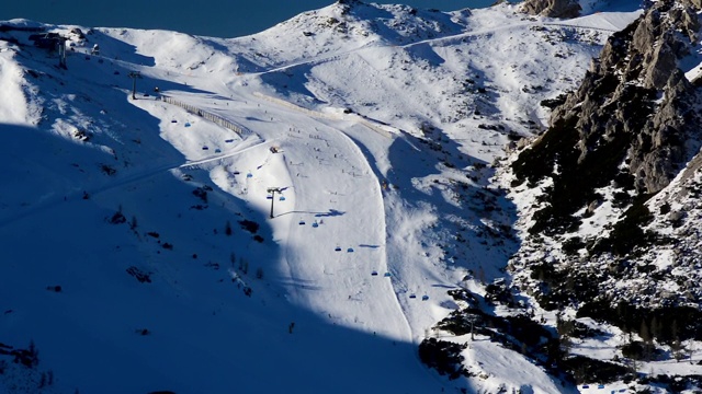 鸟瞰图滑雪坡满滑雪者在阳光明媚的冬天在受欢迎的奥地利滑雪胜地。视频素材