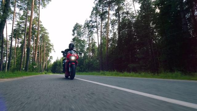 一个骑摩托车的人正沿着森林道路行驶视频素材