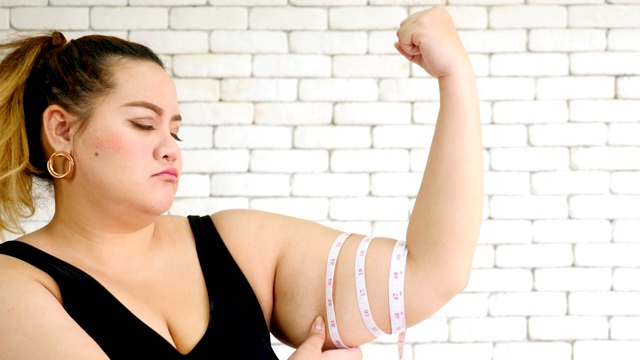 一个不幸的超重妇女用测量尺测量手臂的特写视频素材