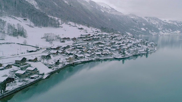 宁静的小城湖畔下着厚厚的新雪，在冬季，鸟瞰图。视频下载