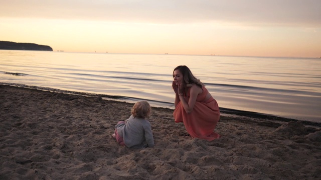 年轻的女人妈妈穿着衣服走在海边在夕阳下与一个小女儿视频素材