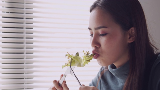 亚洲妇女微笑和吃沙拉在家，健康和生活方式的概念视频素材