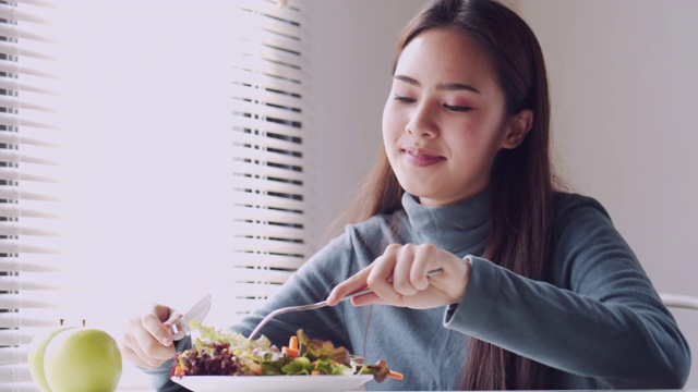 亚洲妇女微笑和吃沙拉在家，健康和生活方式的概念视频素材