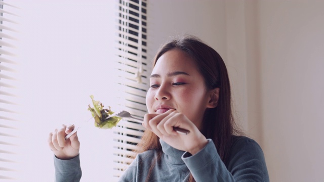 亚洲妇女微笑和吃沙拉在家，健康和生活方式的概念视频素材