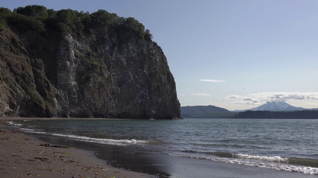 平静的海浪在海上，海滩从黑色的沙子，岩石海岸太平洋。时间流逝视频素材