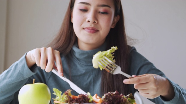 特写亚洲妇女微笑和吃沙拉在家里，健康和生活方式的概念视频素材