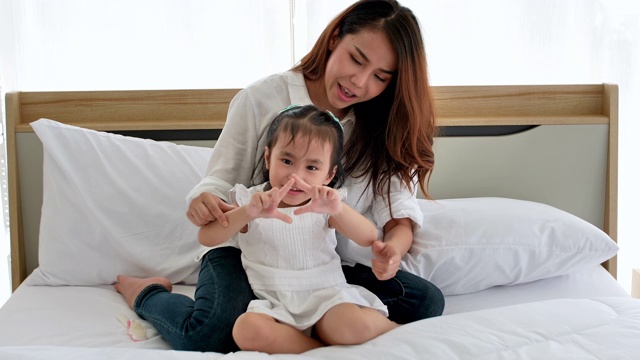 亚洲家庭一起在房子里度过的快乐时光。三岁的母亲和女儿喜欢在床上玩耍。幸福在家里。视频素材