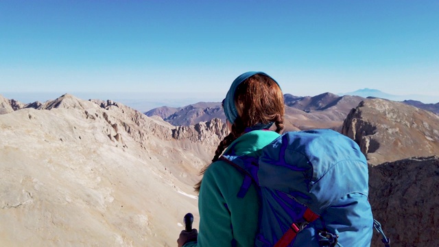 一位女登山运动员正在眺望一座山的顶峰视频素材