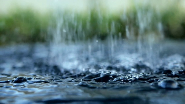 近距离的雨水滴落到水面在雨季视频素材