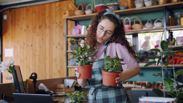 可爱的女售货员在花店拿着植物打电话视频素材