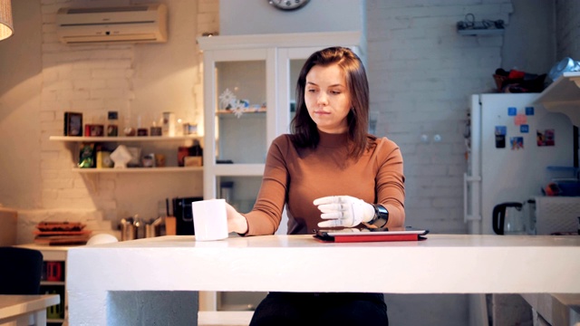 年轻女子正在用她的合成手用杯子喝水视频素材