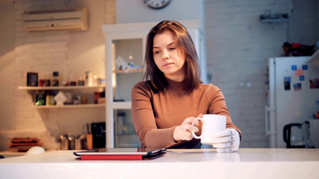 一位拥有仿生手的女士从杯子里喝水并操作平板电脑视频素材