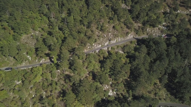 鸟瞰图山形蜿蜒的道路与卡车和汽车。股票。道路交通蜿蜒在高山狭窄的角落，汽车变成绿色的森林视频素材