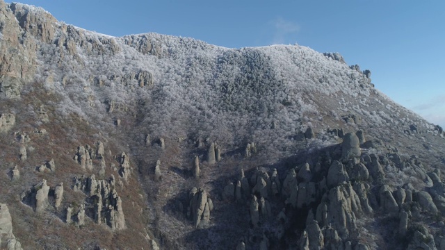 山顶上的景色覆盖着巨大的岩石和雪白的灌木，映衬着湛蓝清澈的天空。鸟瞰图视频素材