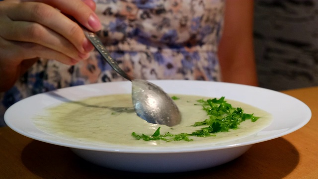 吃素食汤的女人很有食欲。品尝一下在厨房做汤的滋味视频素材