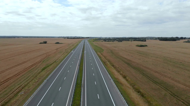 公路旅行在贫瘠的景观高速公路上飞过汽车。4 k。麦田之间的柏油路鸟瞰图。汽车在旱地上行驶的鸟瞰图。视频素材