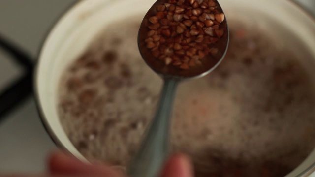 荞麦是在厨房里煮的。沸水蒸汽。用金属勺子检查食物是否煮熟。视频素材