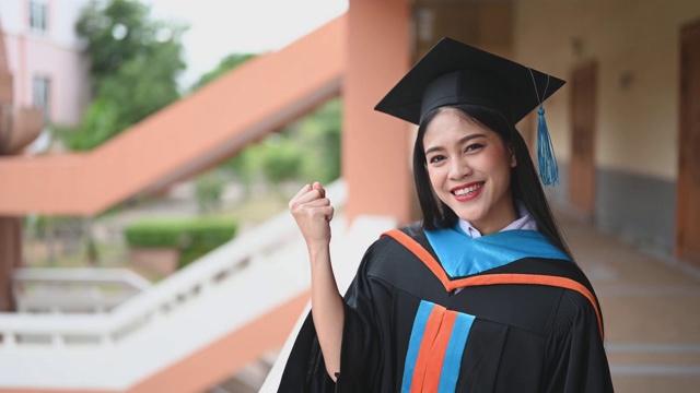 女性肖像，大学毕业生穿着黑色的褶边裙，戴着黑色的帽子和蓝色的流苏。视频素材