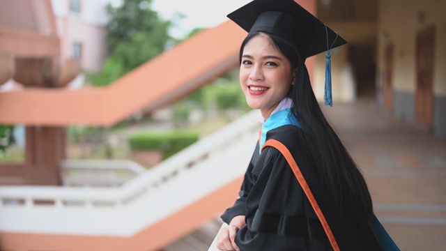 女性肖像，大学毕业生穿着黑色的褶边裙，戴着黑色的帽子和蓝色的流苏。视频素材