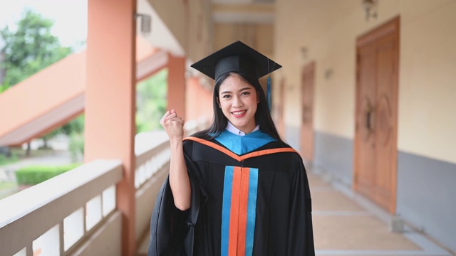 女性肖像，大学毕业生穿着黑色的褶边裙，戴着黑色的帽子和蓝色的流苏。视频素材